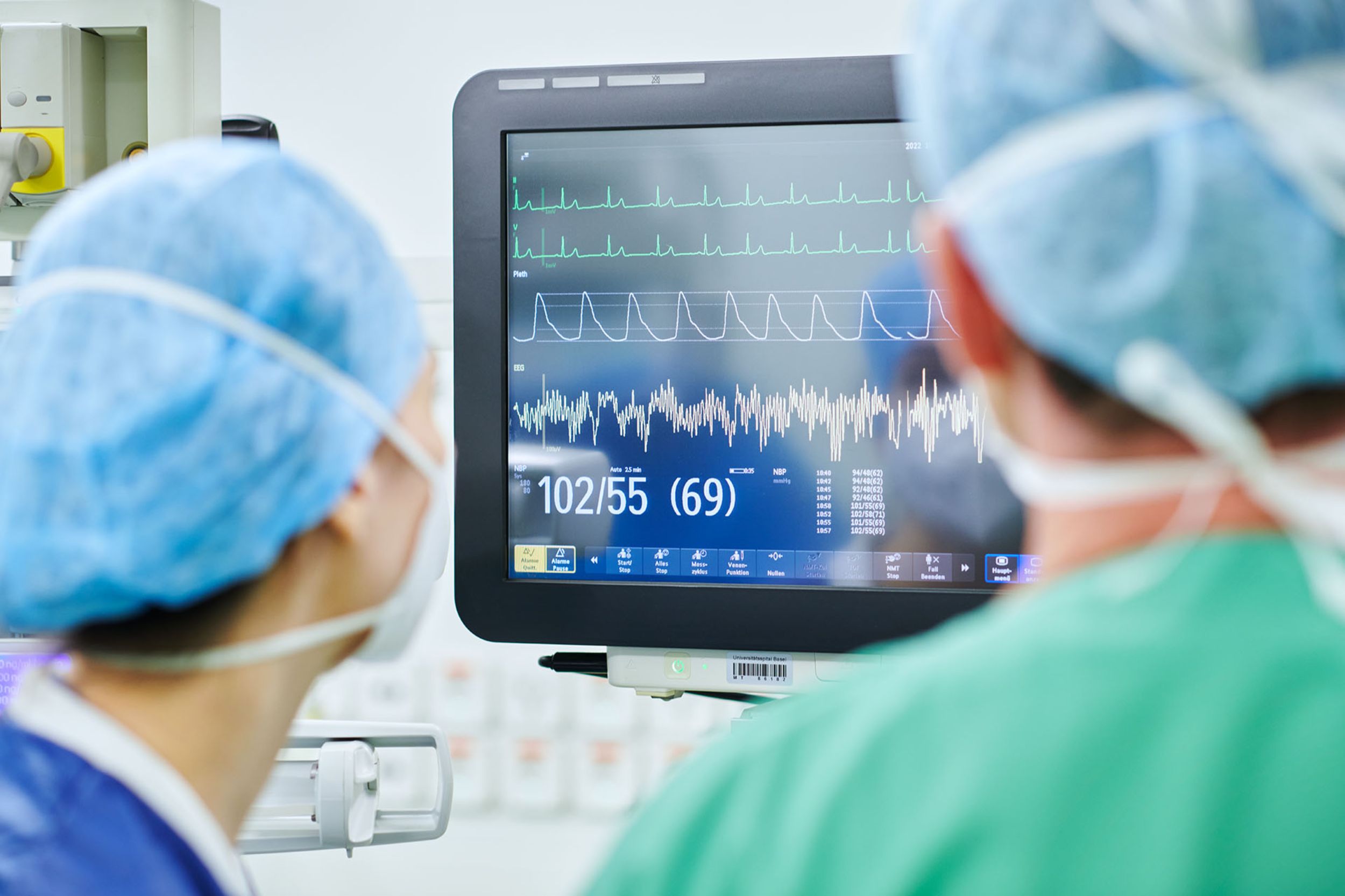 Zwei Personen, die auf dem BIldschirm die Werte des Patienten überwachen.
