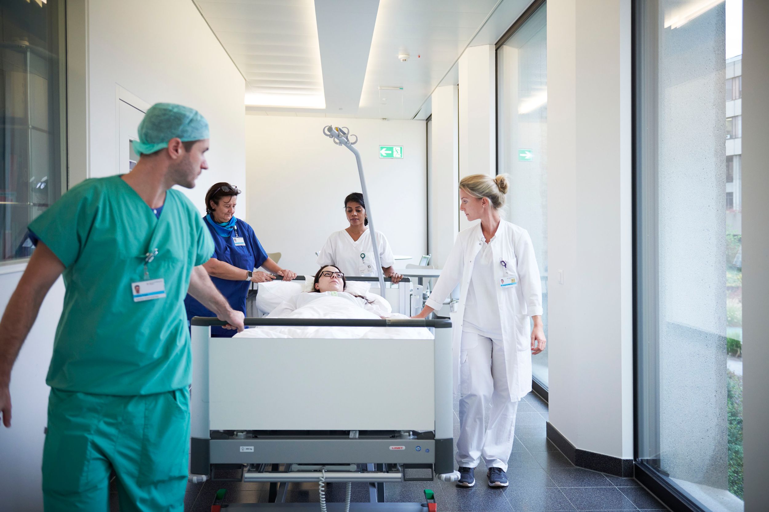Ärzte und Pfleger schieben Patientin durch Gang