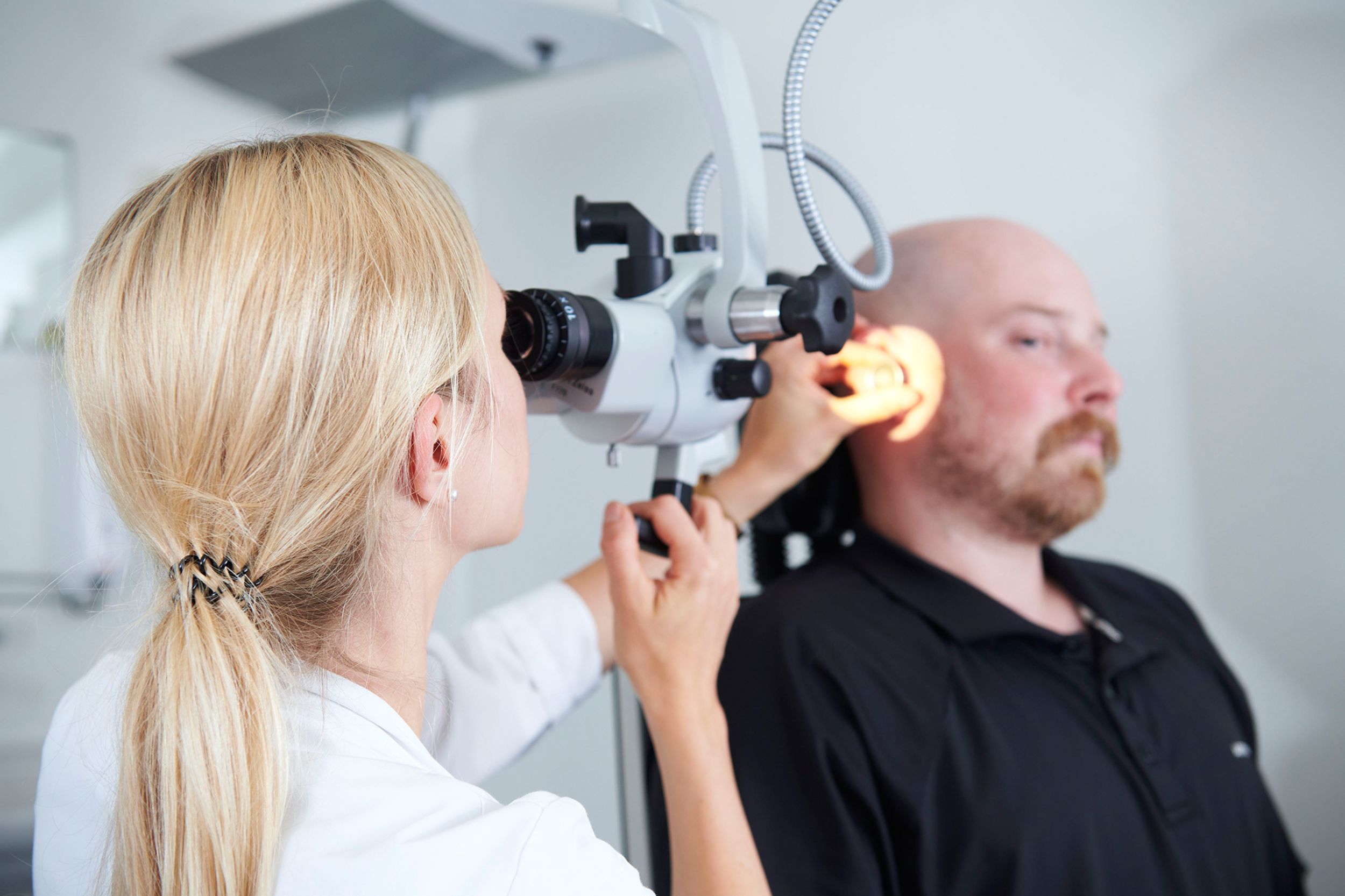 Ärztin untersucht Ohr von Patient