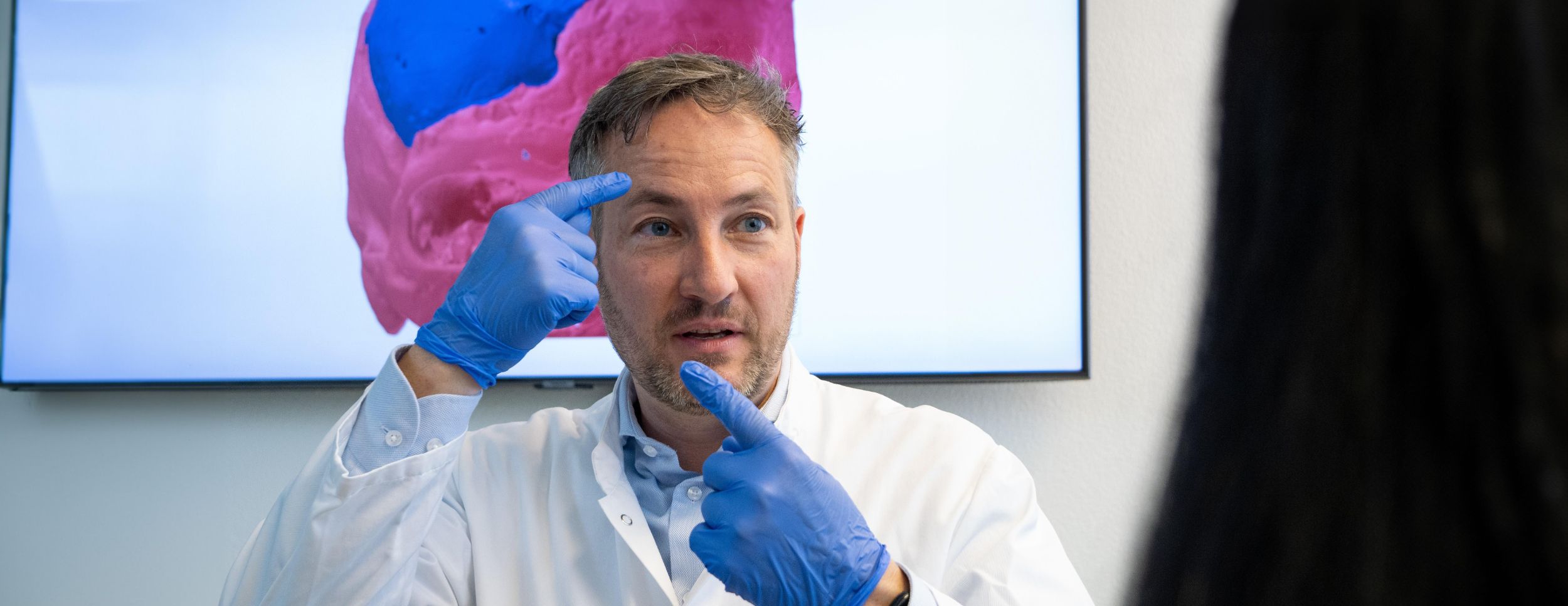 Dr. Andreas Müller erklärt einem Kollegen etwas auf einem Bildschirm