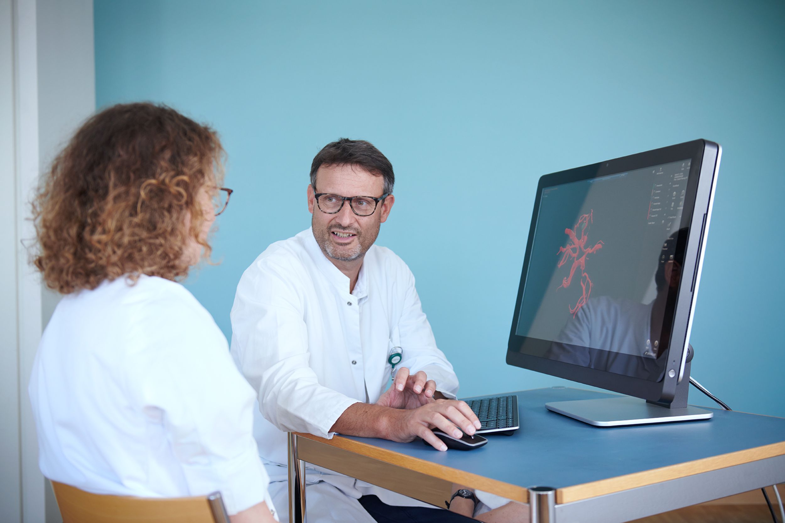 Le professeur Luigi Mariani en conversation avec un patient dans la salle d'attente du service de chirurgie