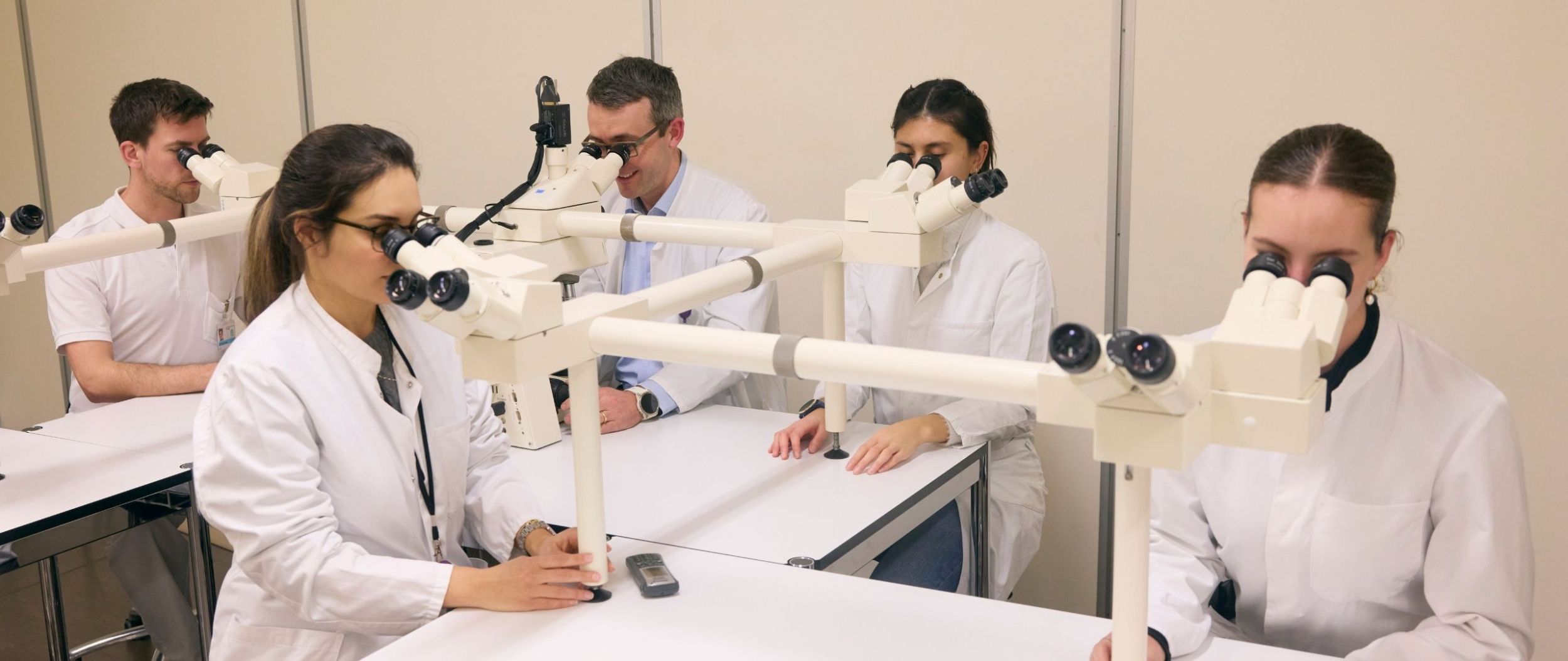 Eine Gruppe Lernender vor Mikroskopen