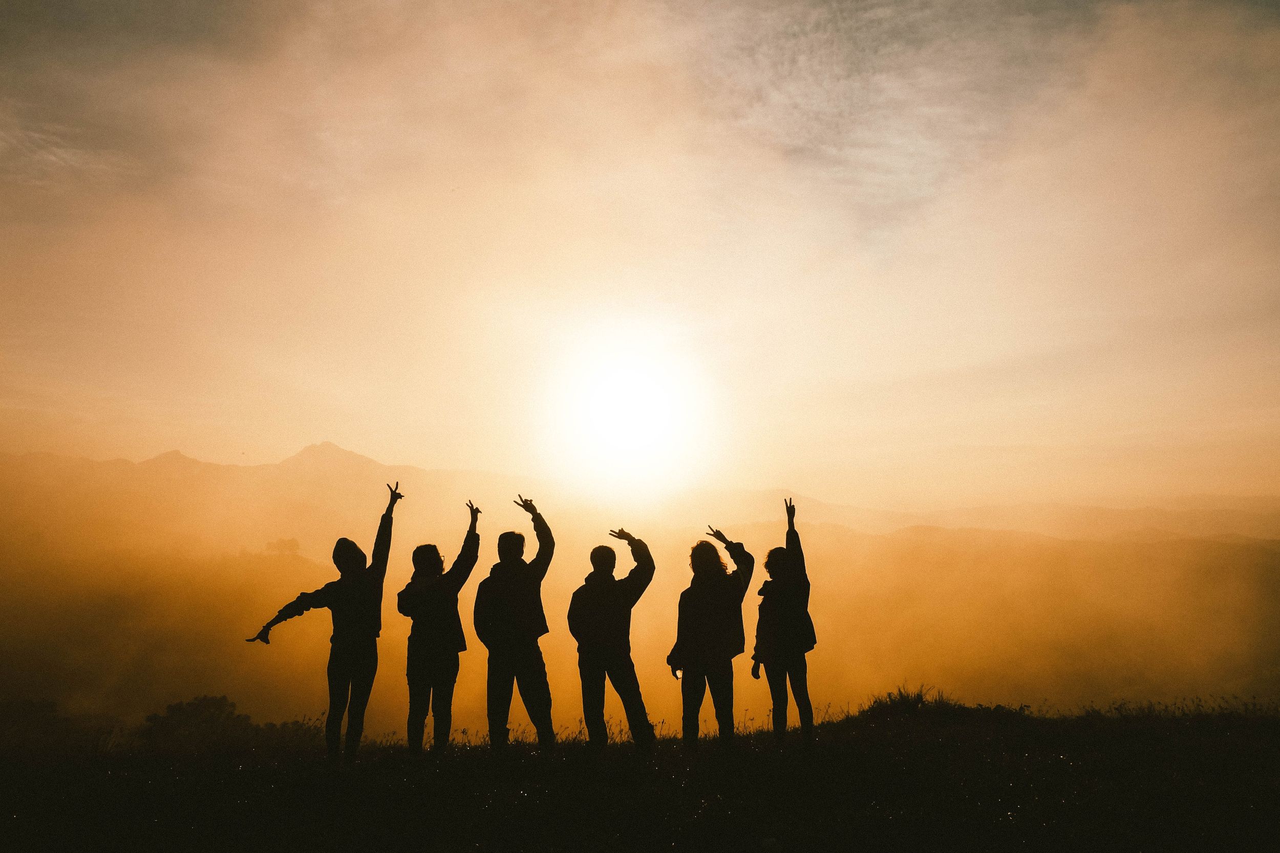 Gruppe vor Sonnenaufgang mit den Händen in der Luft