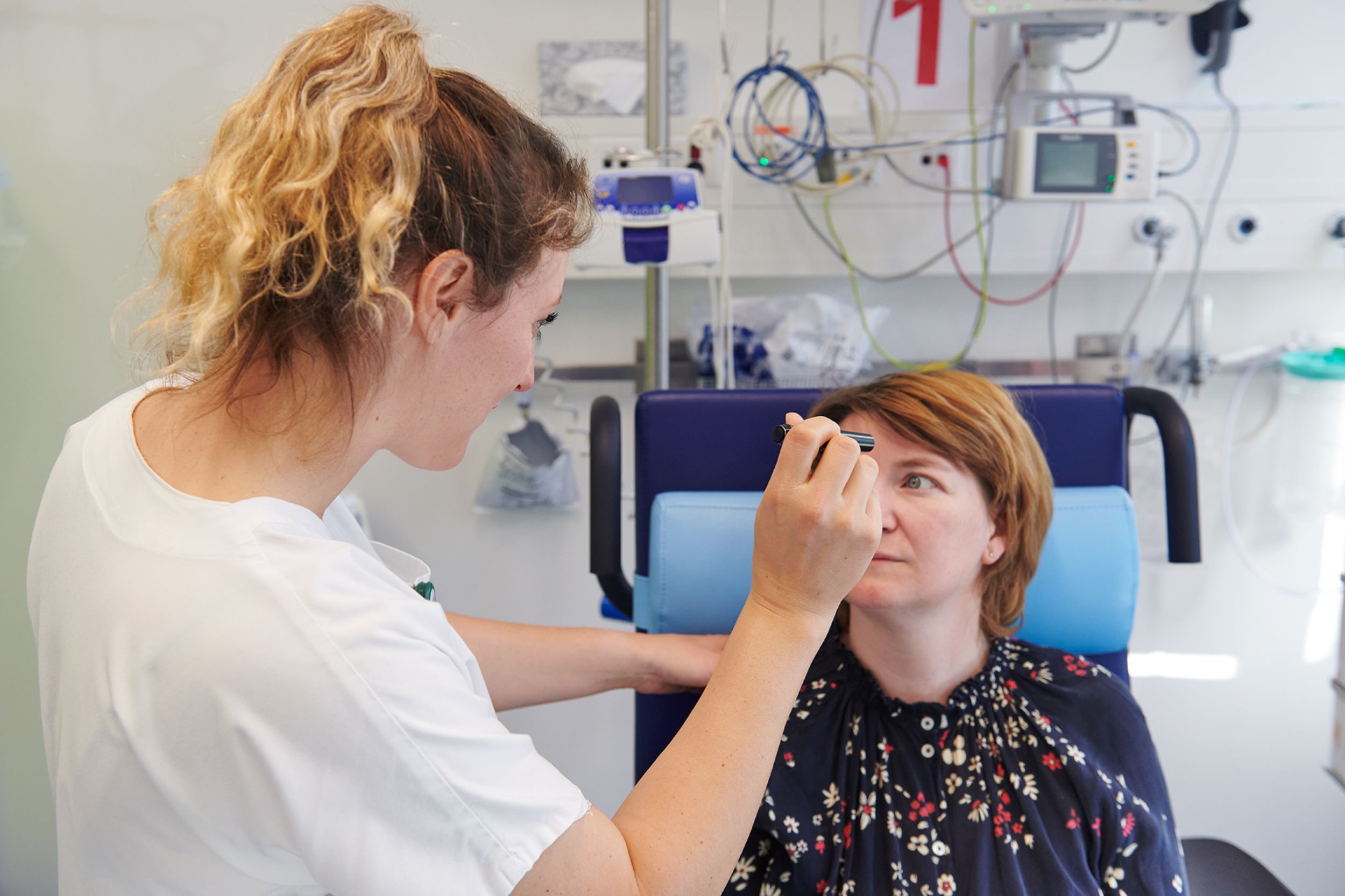 Mitarbeiterin des Notfallzentrums untersucht Reaktion von Patientin mit Taschenlampe