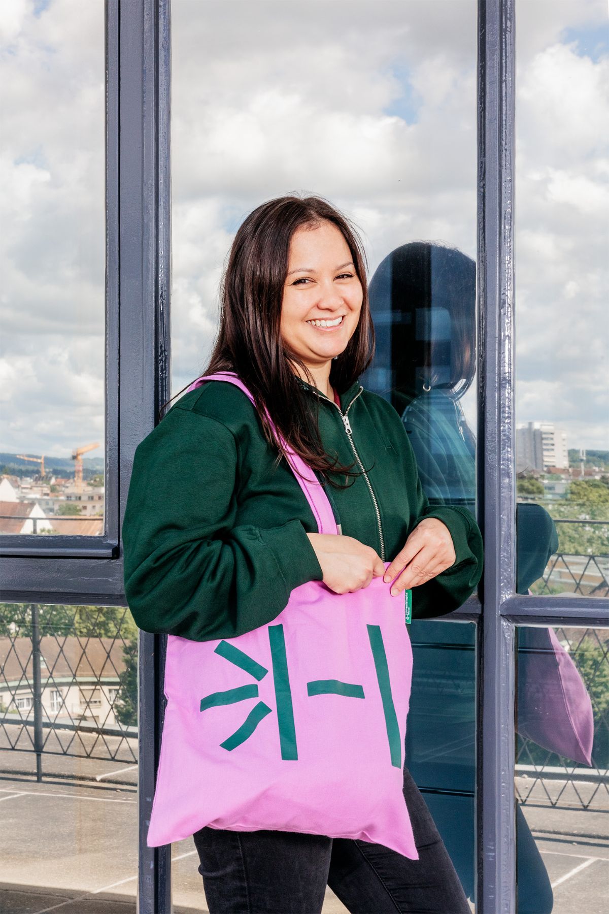 Mitarbeiterin mit dunkelgrünem Hoodie und pinkem Totebag USB Merchandise