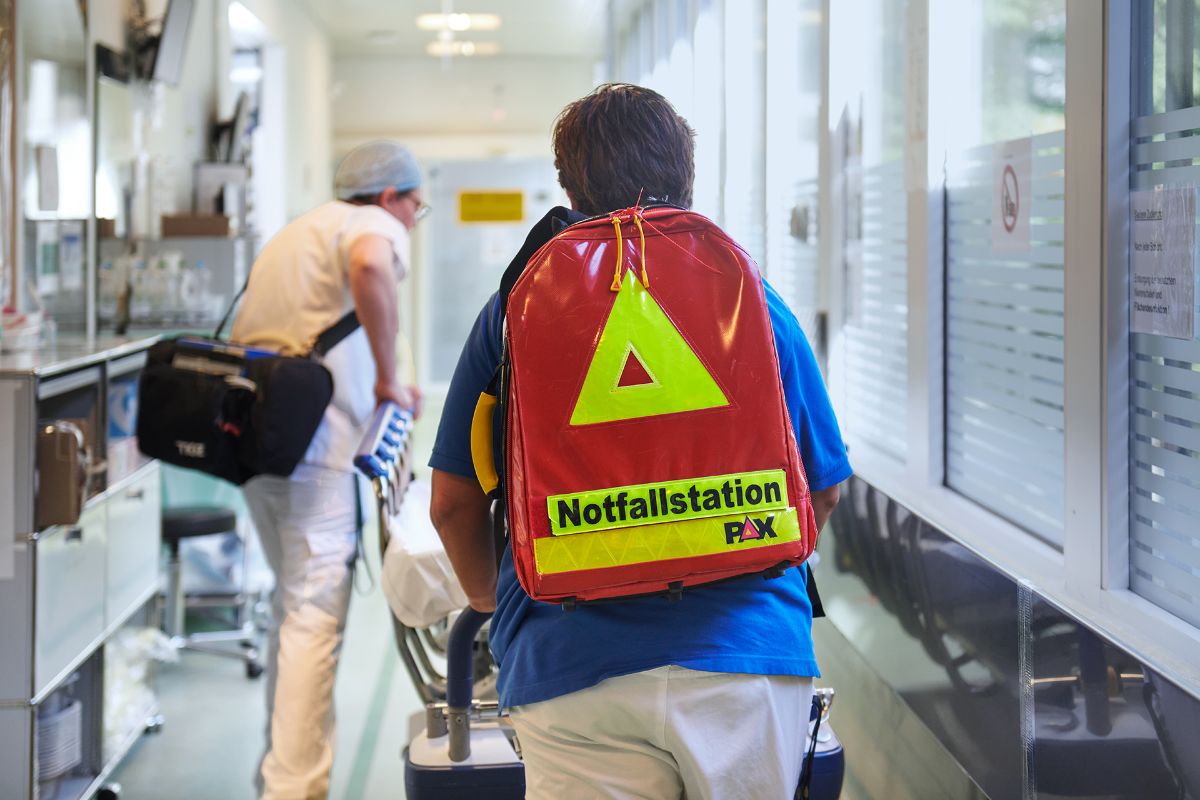 Notfall-Ärztin mit Pfleger schieben Bett durch Gang