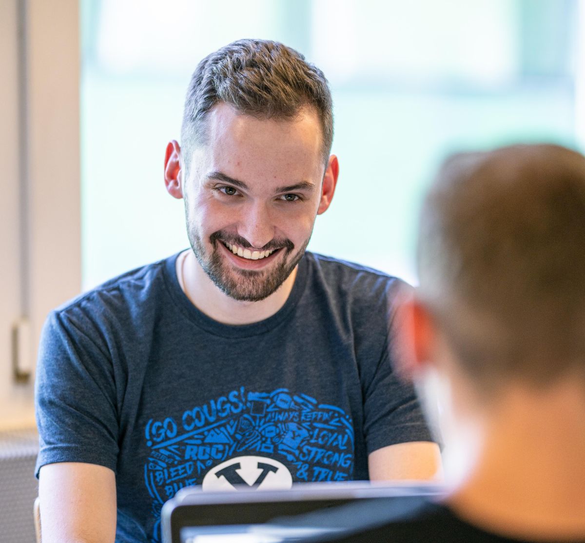 Informatiker EFZ in Ausbildung spricht mit einem Kollegen am Arbeitsplatz