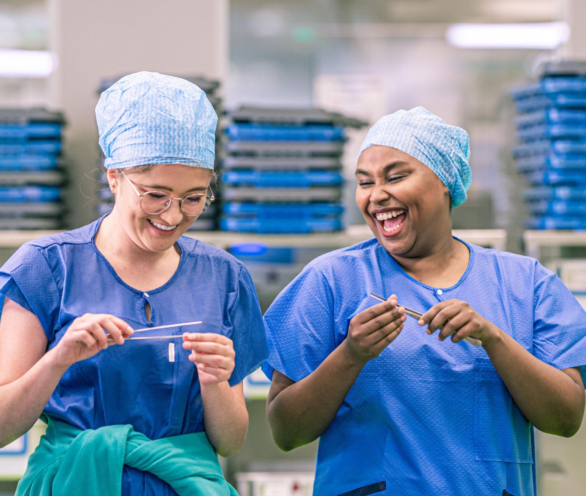 Deux technologues en dispositifs médicaux en formation tiennent du matériel médical et rient ensemble