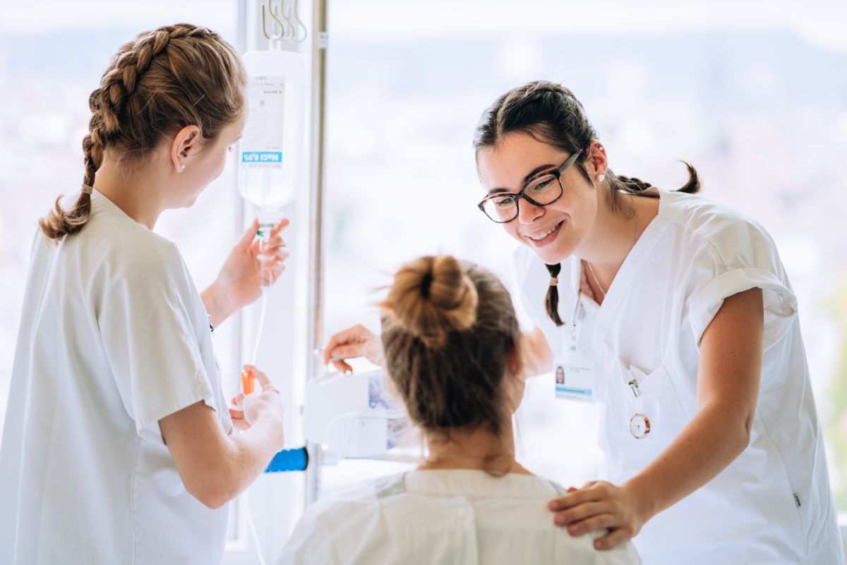 zwei Pflegefachfrauen kümmern sich um eine Patientin