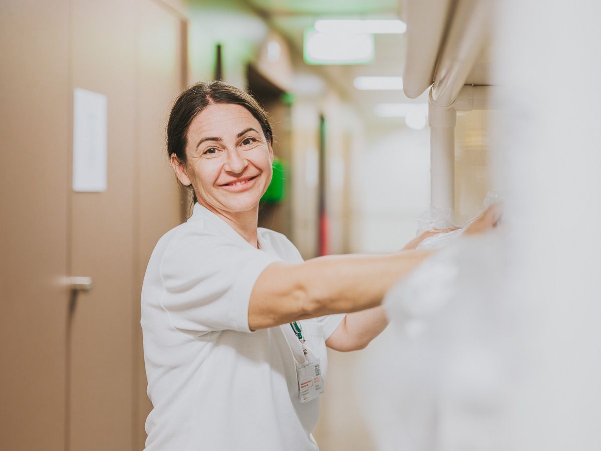 Fröhliche Pflegefachfrau im Flur bei der Arbeit.
