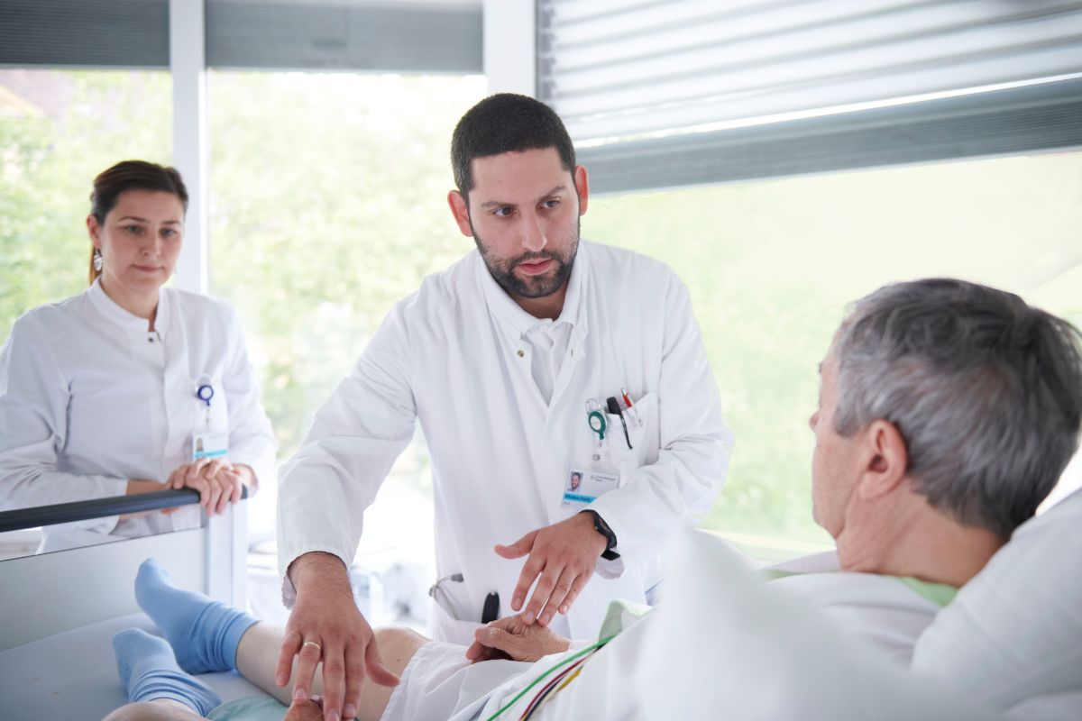 Arzt und Ärztin bei der Behandlung eines bettlägerigen Patienten